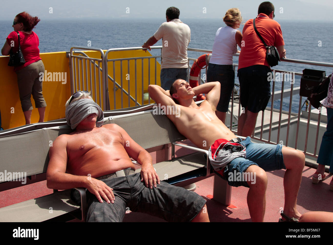 Two men sunbathing on the deck of the ferry to El Hierro from Tenerife Canary Islands Spain Stock Photo