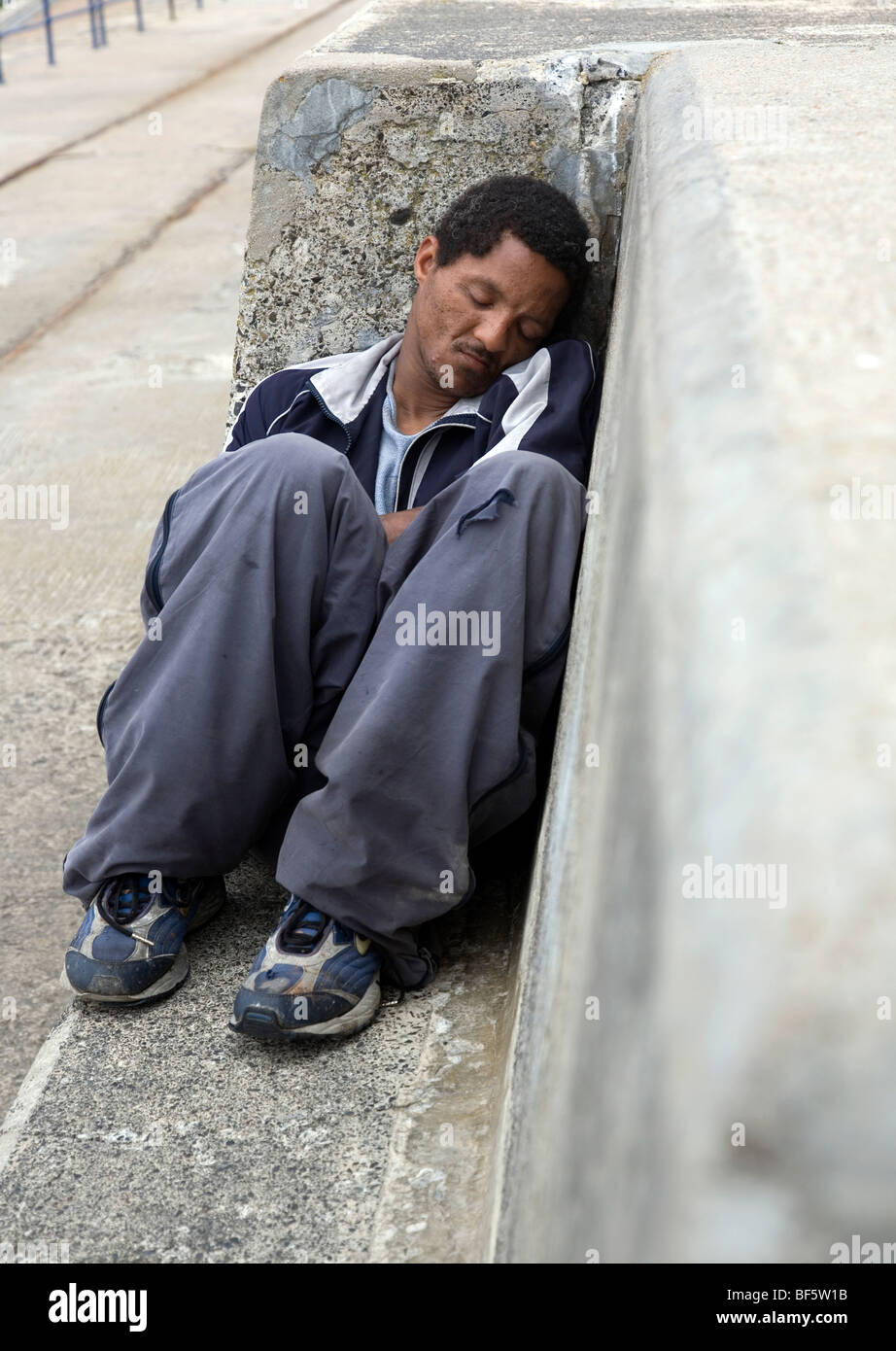 Man sleeping on cement bench Stock Photo