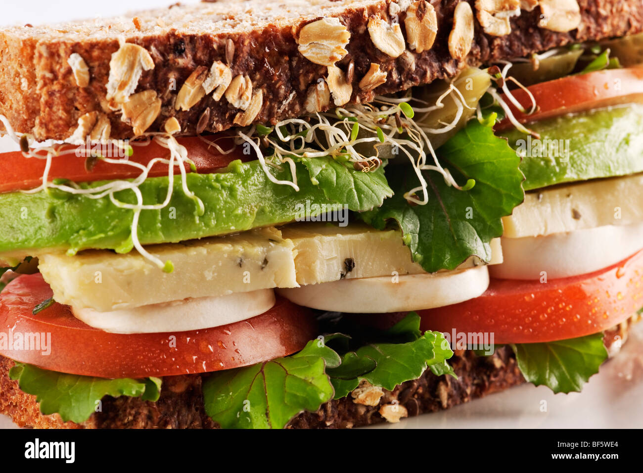 Vegetarian health bread sandwich with avocado, cheese, mushrooms, lettuce, sprouts and tomatoes Stock Photo