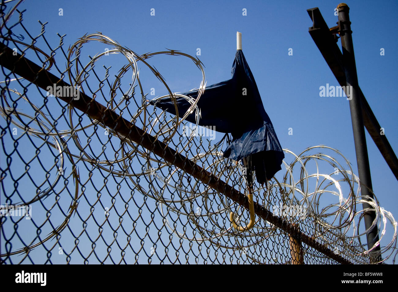 An umbrella stands upright atop a chain link fence Stock Photo Alamy