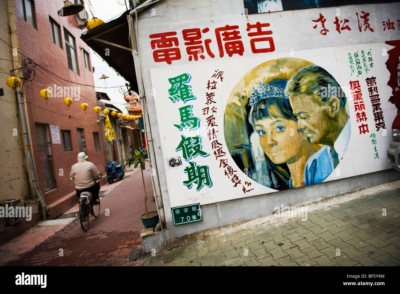 A man on a bicycle rides pass an ad for an Audrey Hepburn movie in Taipei, Taiwan. Stock Photo