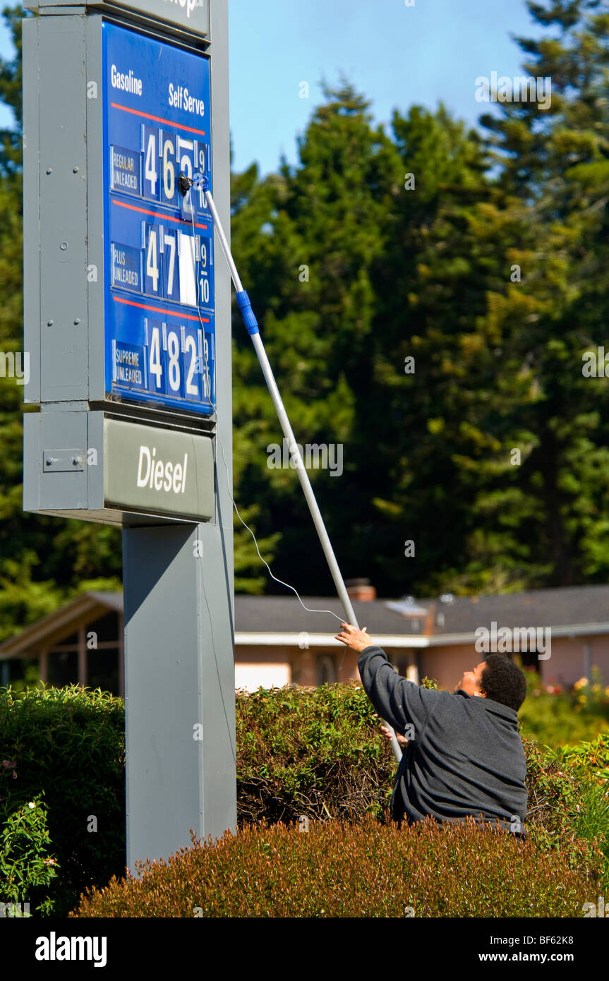 Gas station attendant using suction pole to change gas prices during summer of 2008 when prices rose daily, California Stock Photo