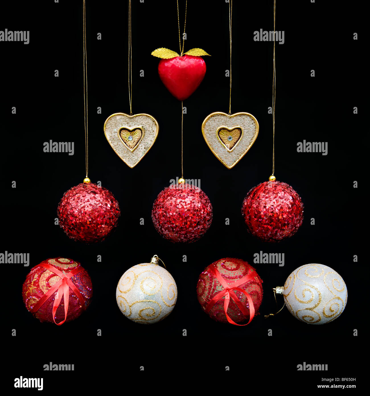Modern picture of mixed red and gold Christmas decorations and baubles shaped into a Christmas tree design on black background Stock Photo