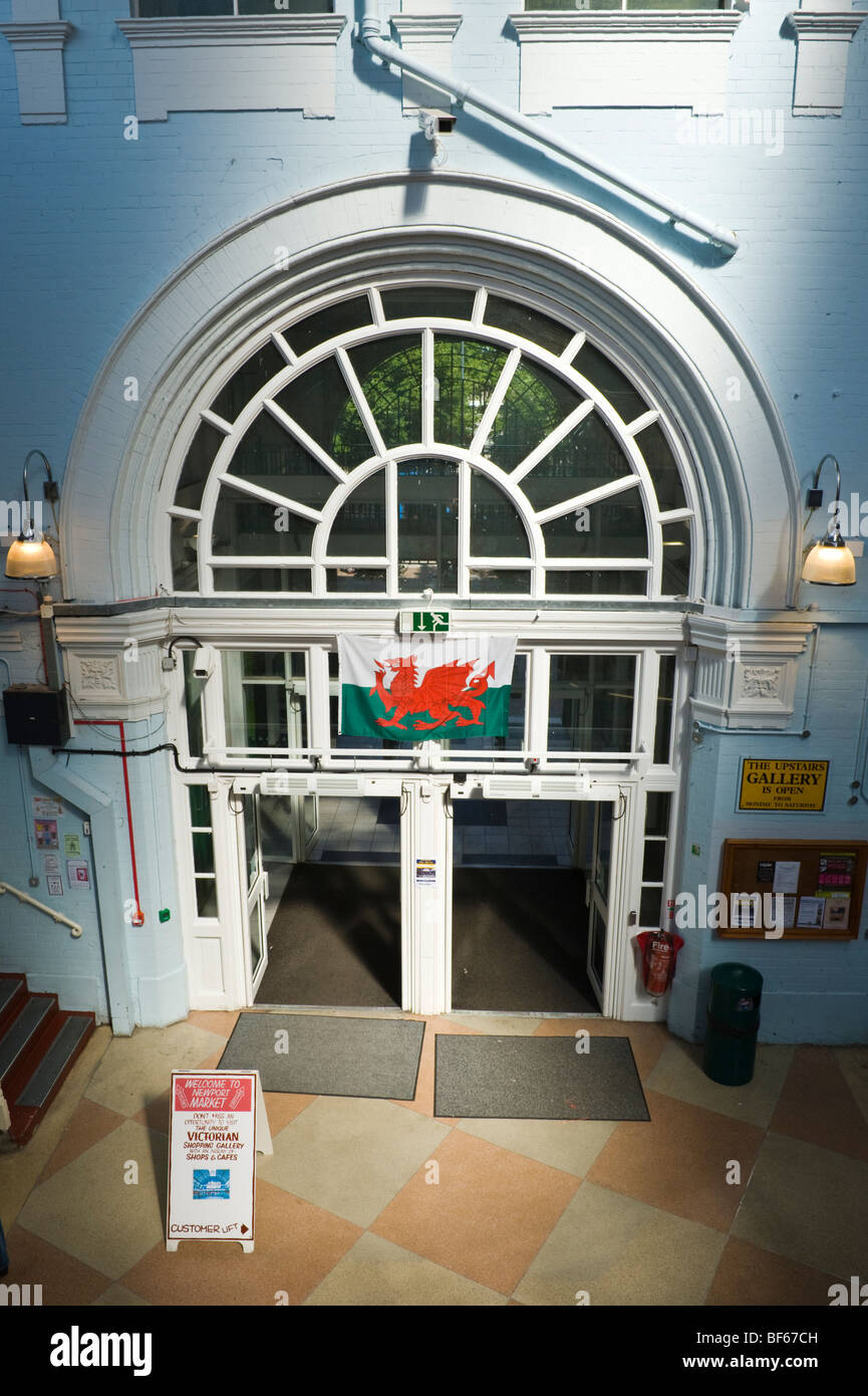 Welsh red dragon flag hanging over entrance with glazed fanlight to indoor market in city of Newport South Wales UK Stock Photo