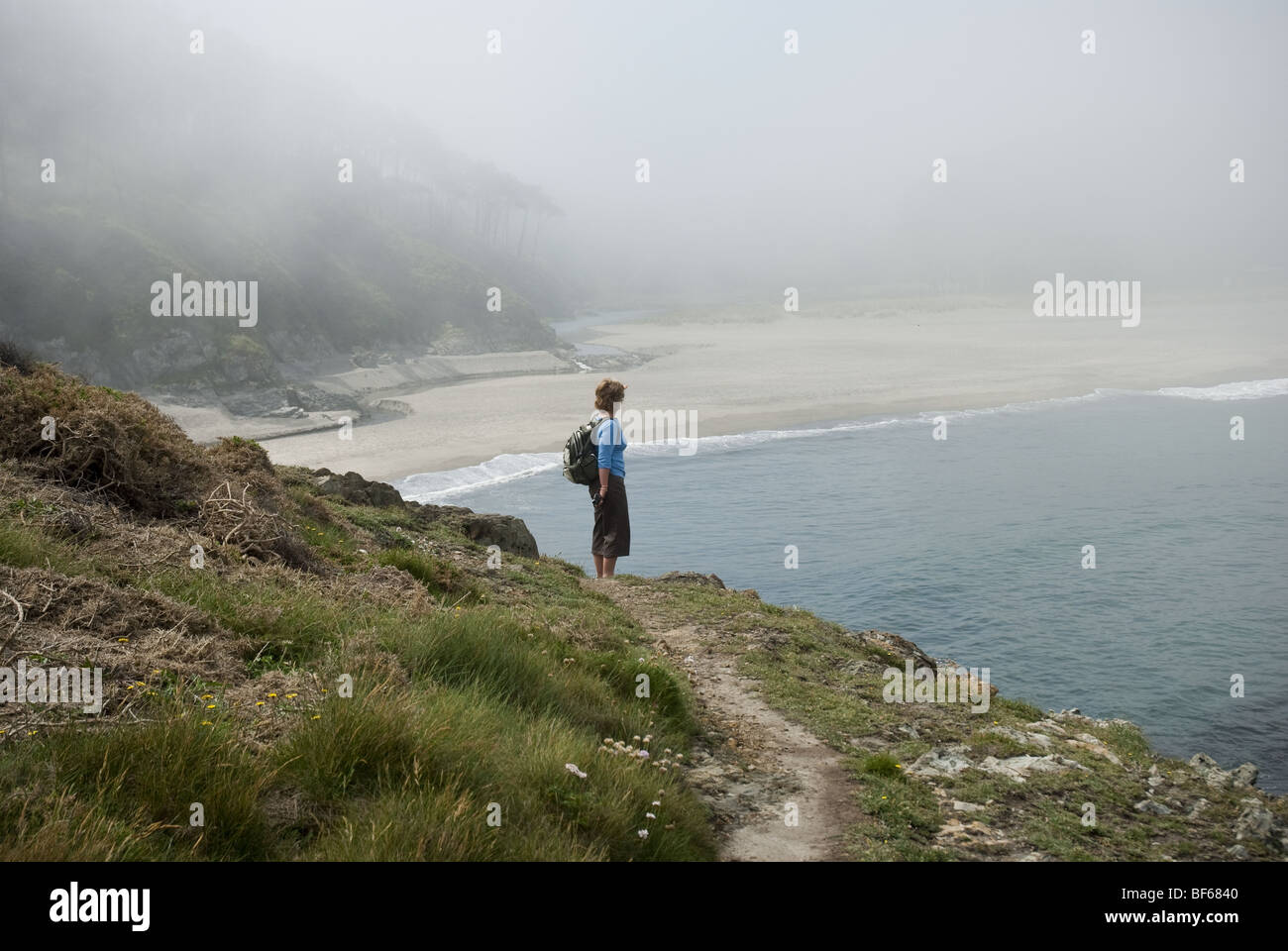A single female admires the view from the cliffs at Playa del Otur beach in Asturias, northern Spain. Stock Photo