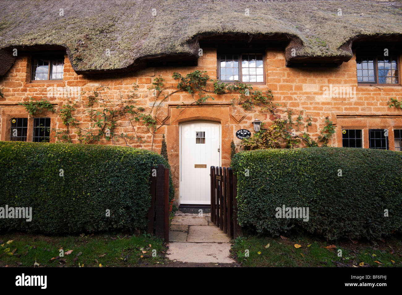 Bee Bole Cottage, a thatched cottage made of local ironstone, in Great Tew, Oxfordshire. Stock Photo