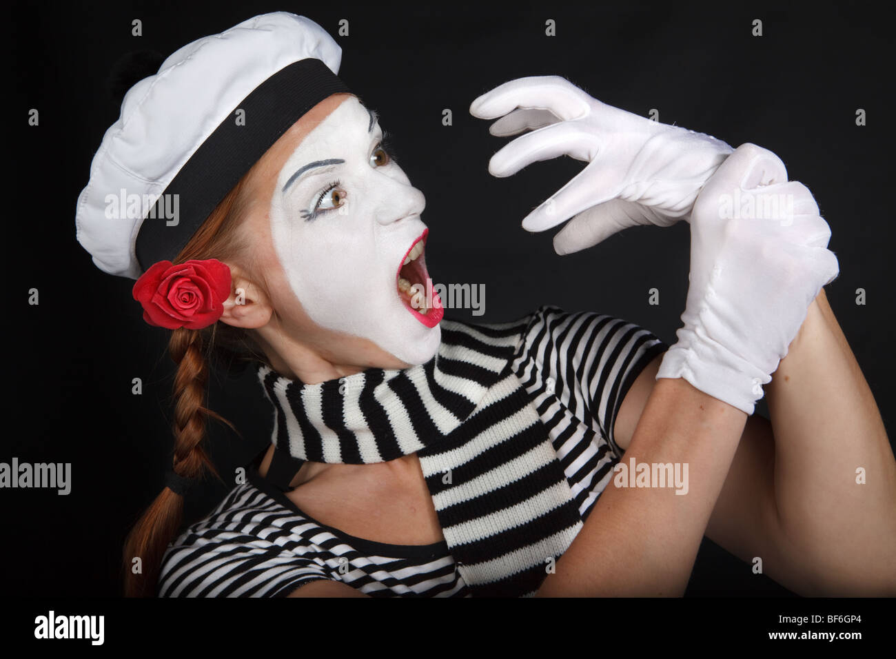 Portrait of a young lady dressed up as a mime isolated over black ...