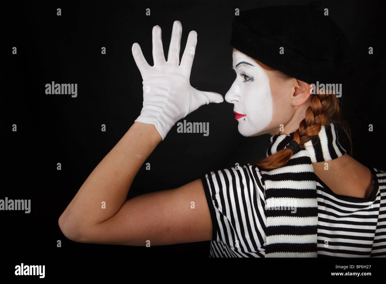 Portrait of a young lady dressed up as a mime isolated over black ...