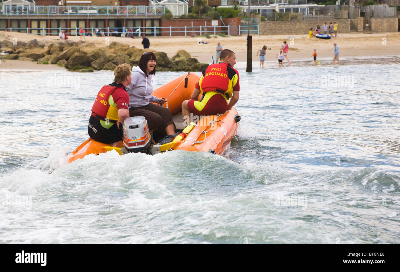 A woman is rescued from a boat by RNLI lifeguards, to be put ashore at Sandbanks, Poole, Dorset. UK. Stock Photo