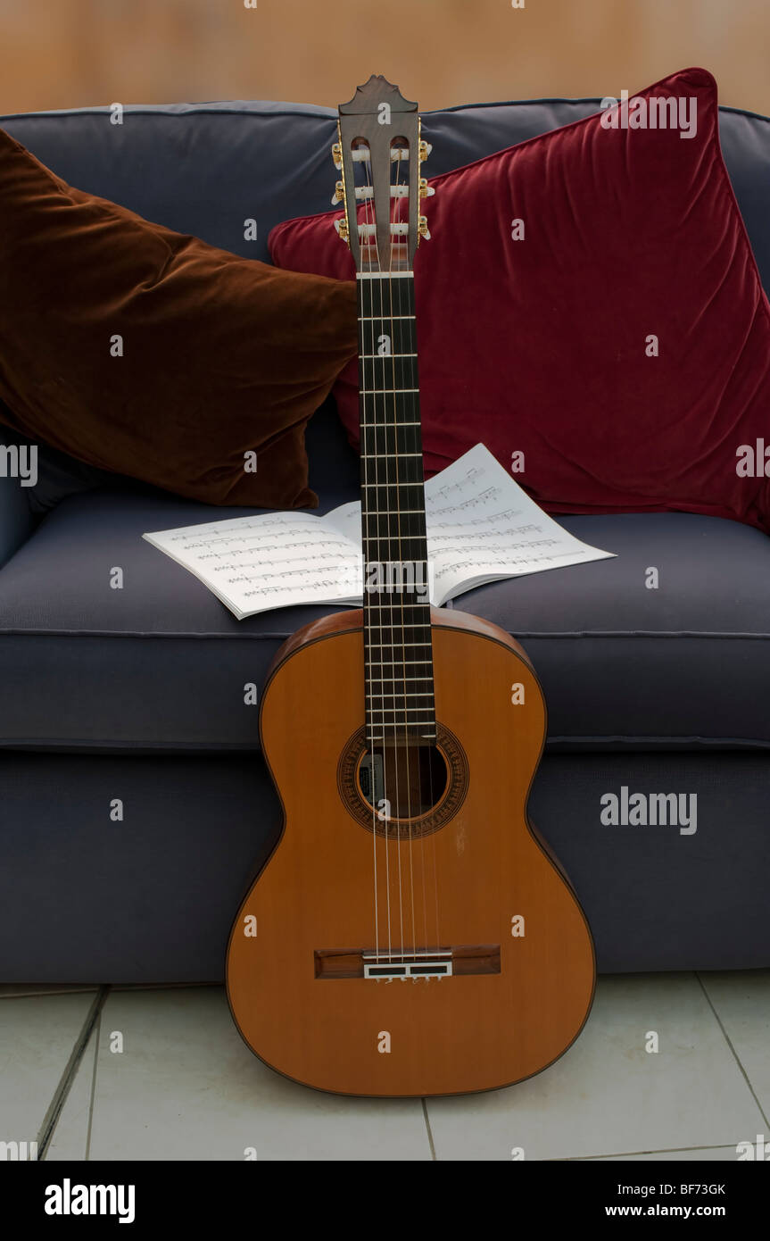 classical guitar leaning on sofa with sheet music Stock Photo