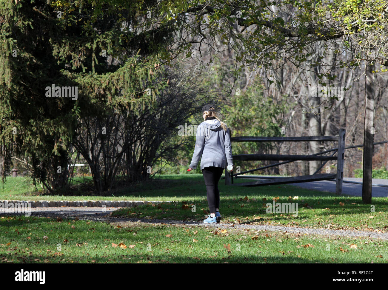 A blond woman girl with pigtails walking in the park for exercise. An autumn day in the park. Stock Photo