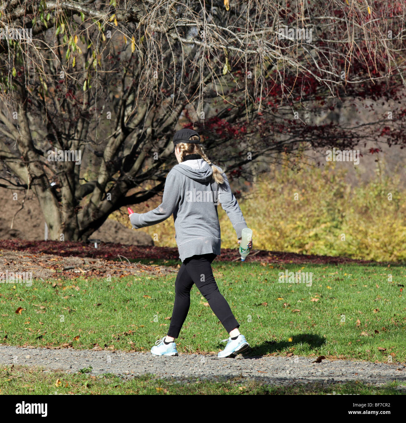 A blond woman girl with pigtails walking in the park for exercise. An autumn day in the park. Stock Photo