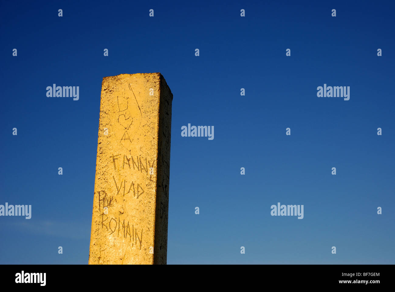 Yellow pole with graffiti against blue sky Stock Photo