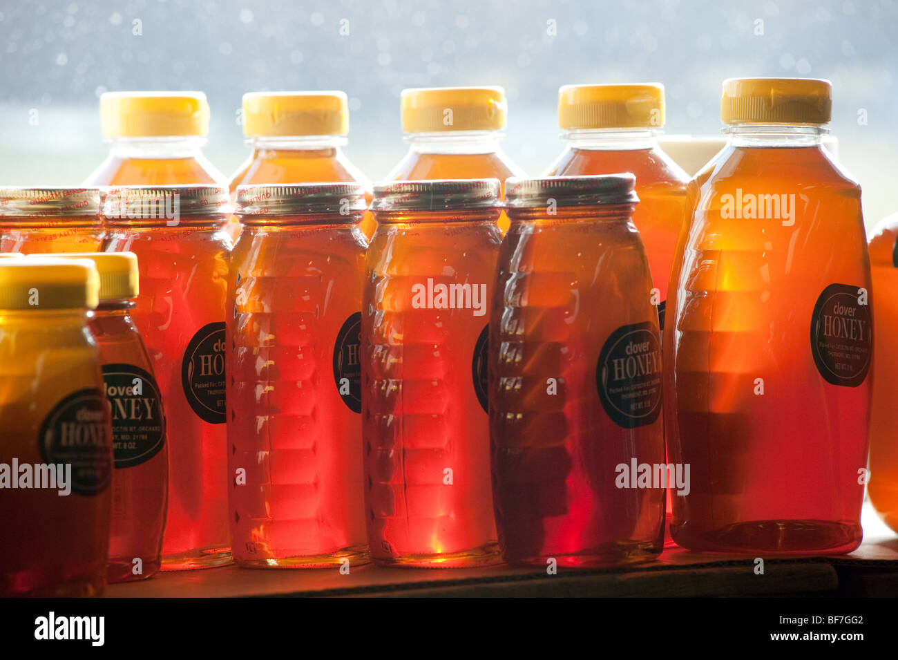 Large, medium and small bottles of honey on window sill Stock Photo