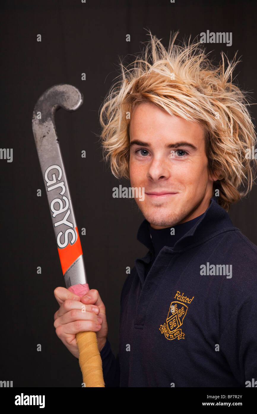UK, Britain. Head and shoulders portrait of a smiling young man wearing a hockey shirt and holding a stick Stock Photo