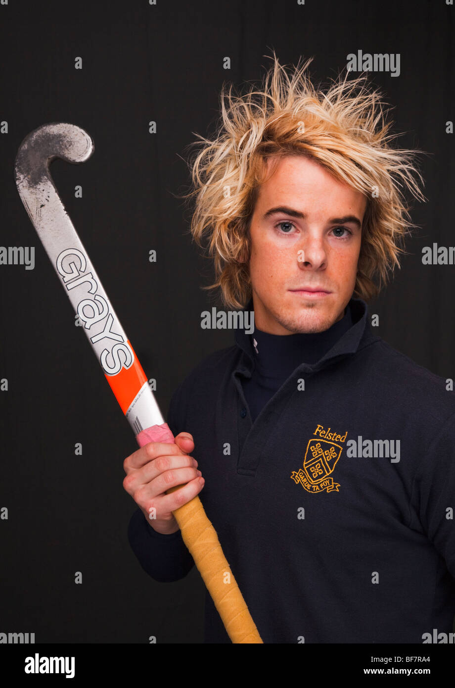 Head and shoulders portrait of a determined young man wearing a hockey shirt and holding a stick. UK, Britain Stock Photo