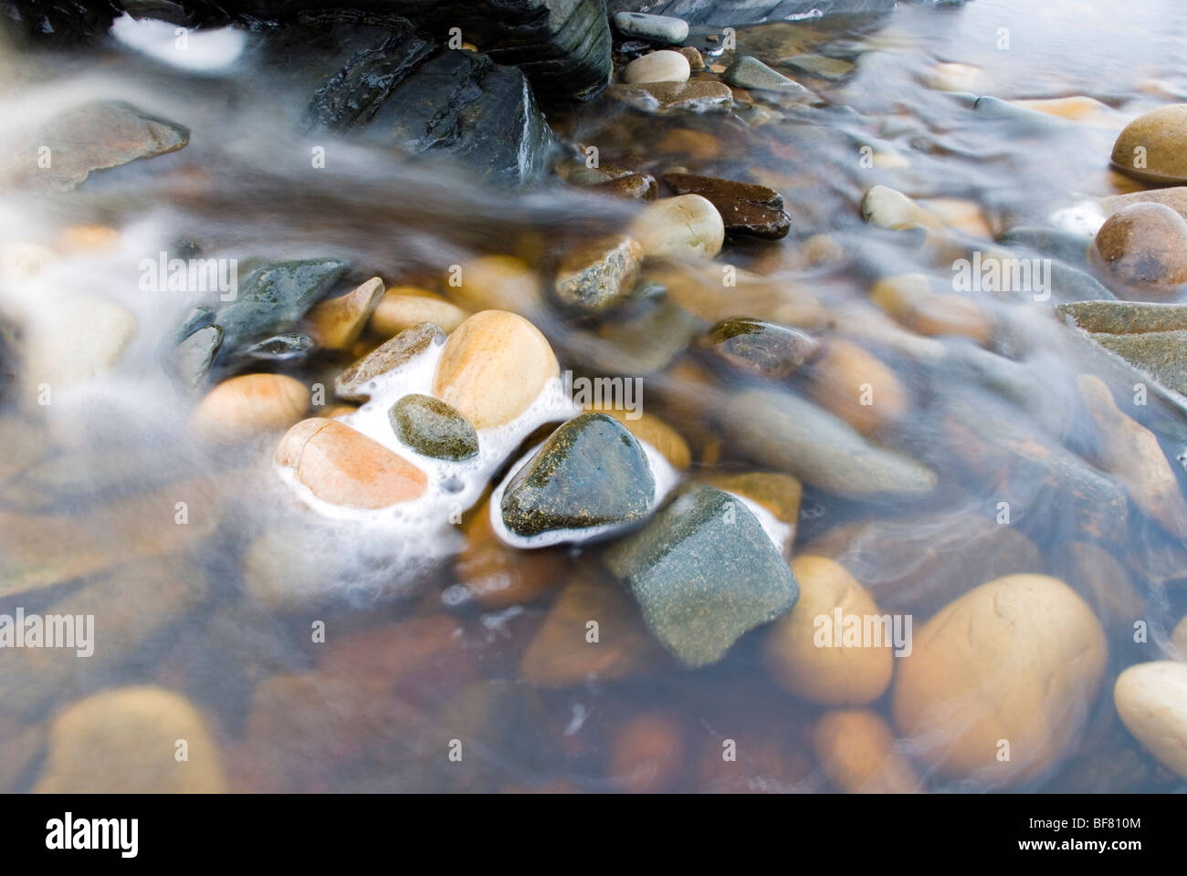 Fresh water running over rocks in a stream to the ocean Stock Photo