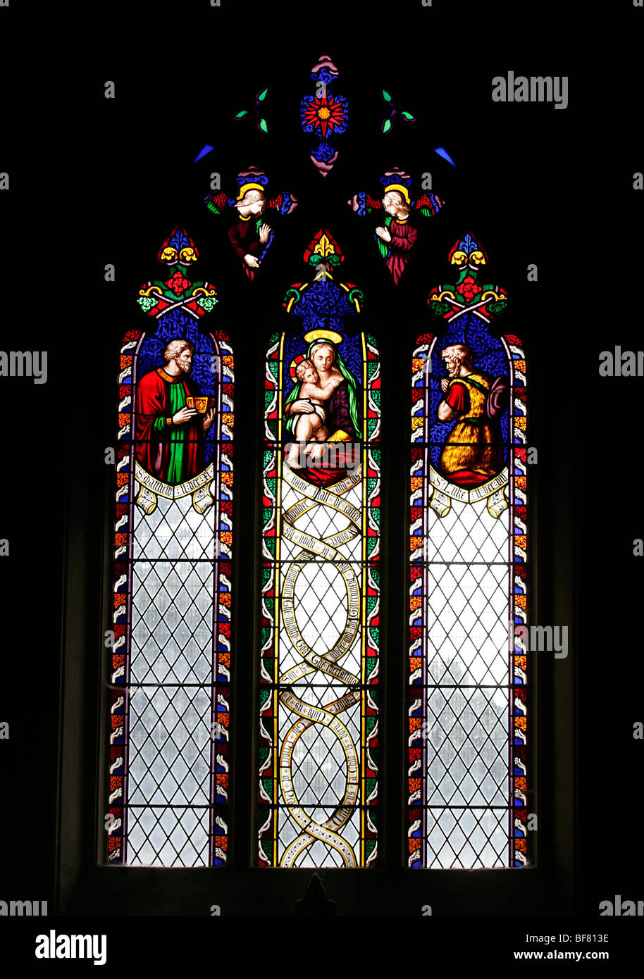 A stained glass window depicting the Madonna and Child flanked by Saints Luke & Matthew, Leigh Delamere, Wiltshire Stock Photo