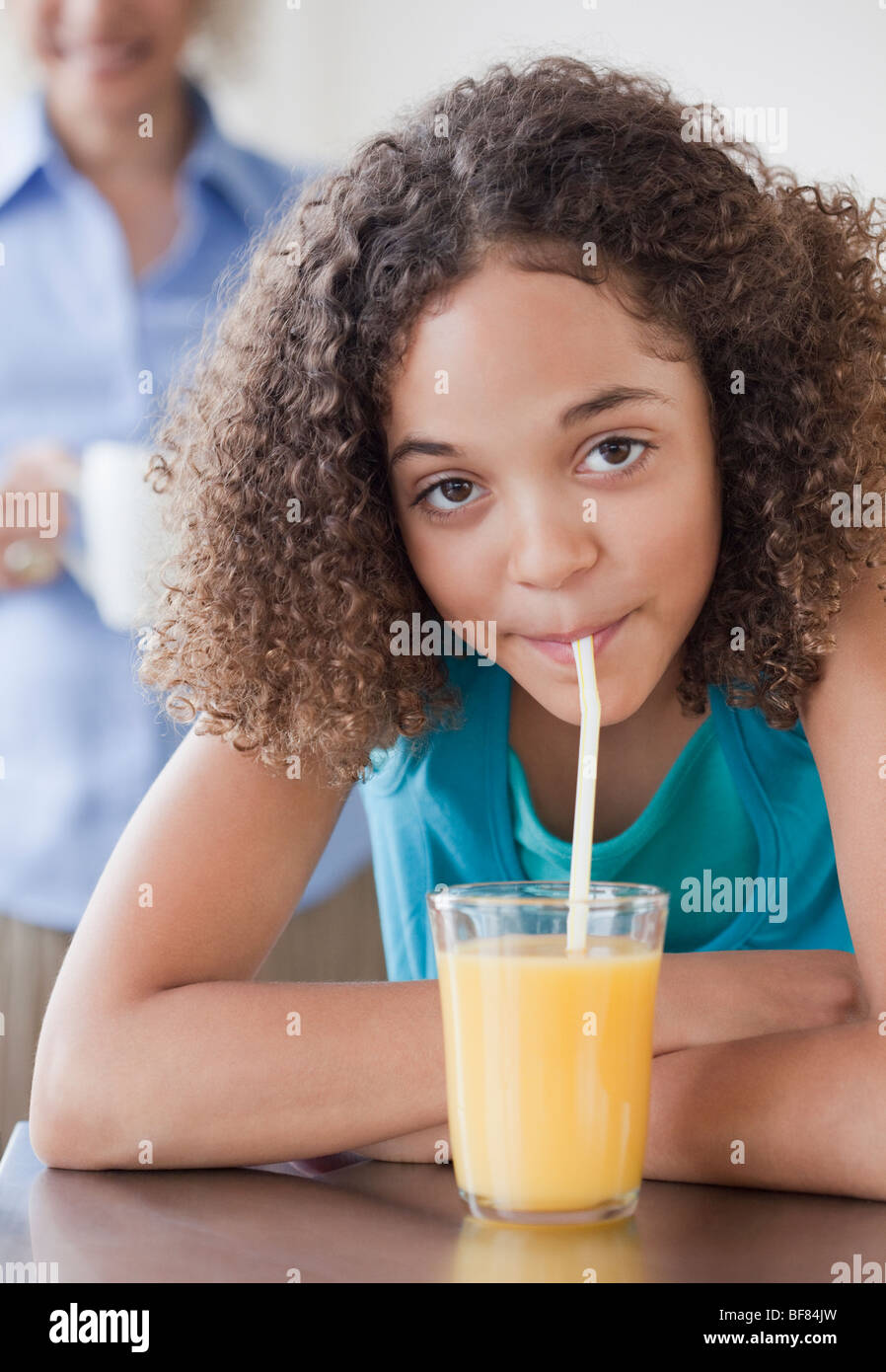 Mixed race girl drinking orange juice with straw Stock Photo Alamy