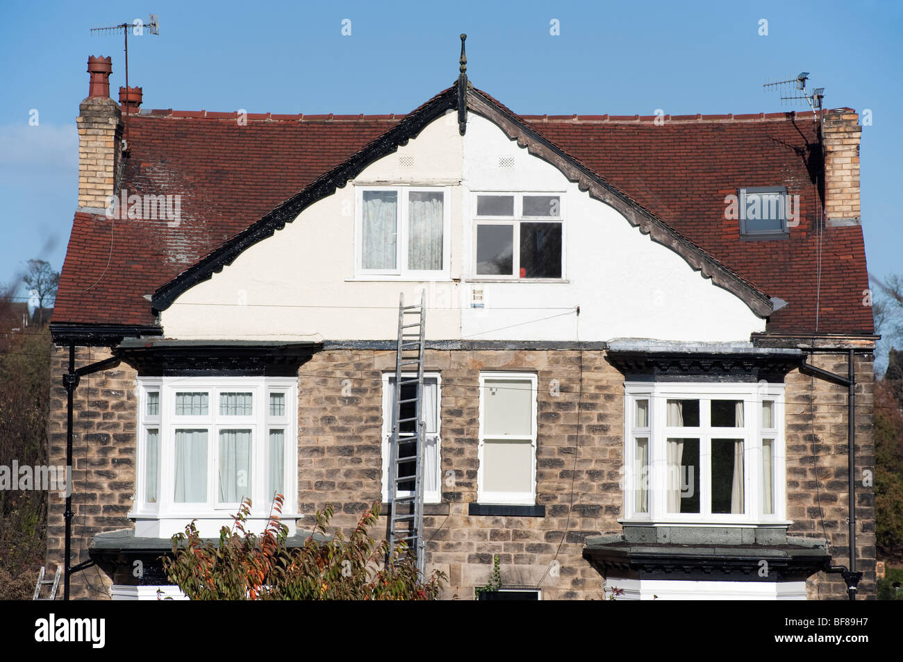 Ladder against a stone fronted Semi detached house Stock Photo