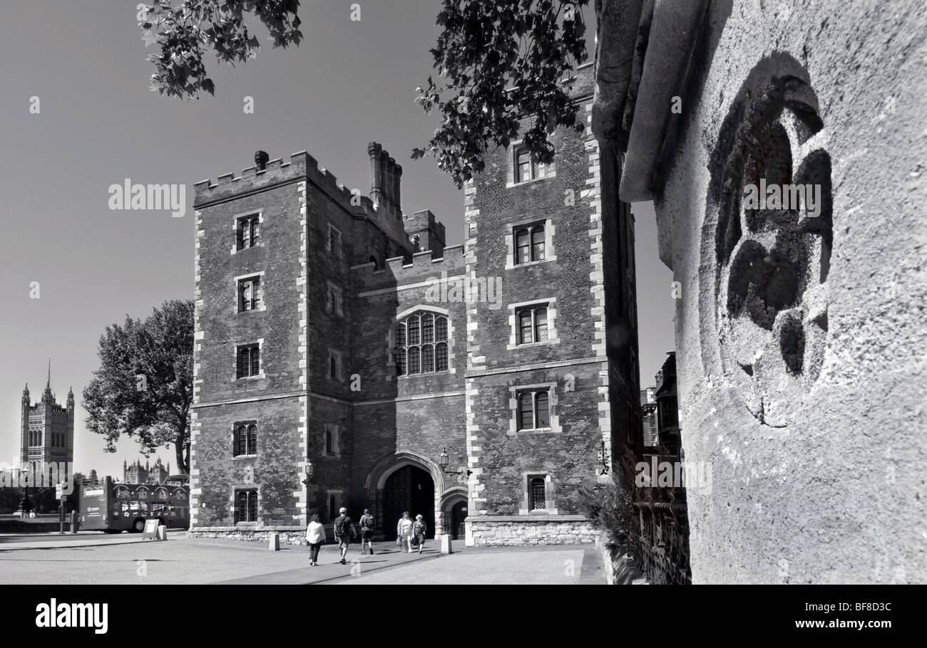 Tudor facade and gatehouse entrance to Lambeth Palace with Houses of Parliament and tourist bus behind Lambeth London UK B+W Stock Photo