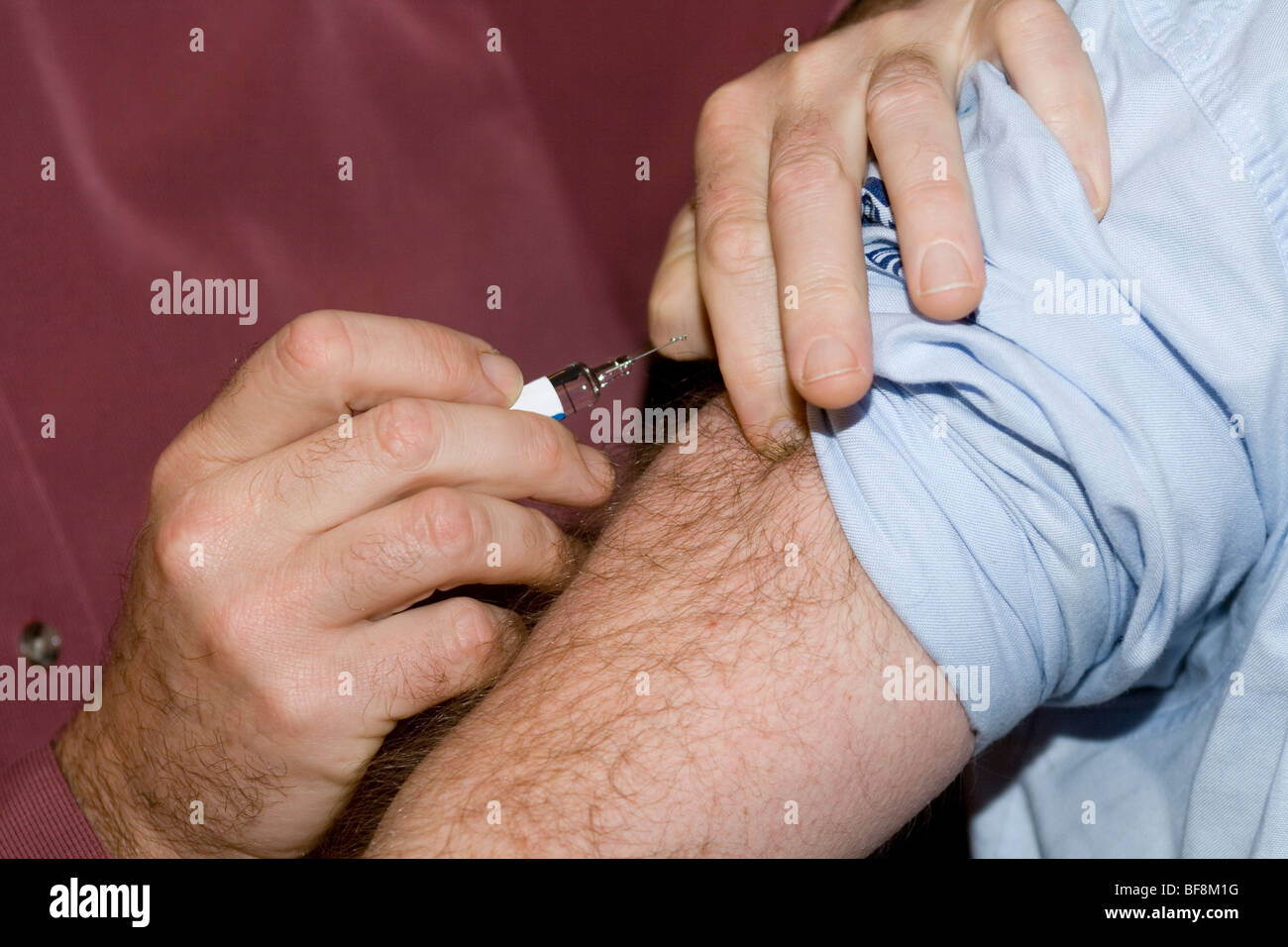 Doctor puts syringe in male hairy arm Stock Photo