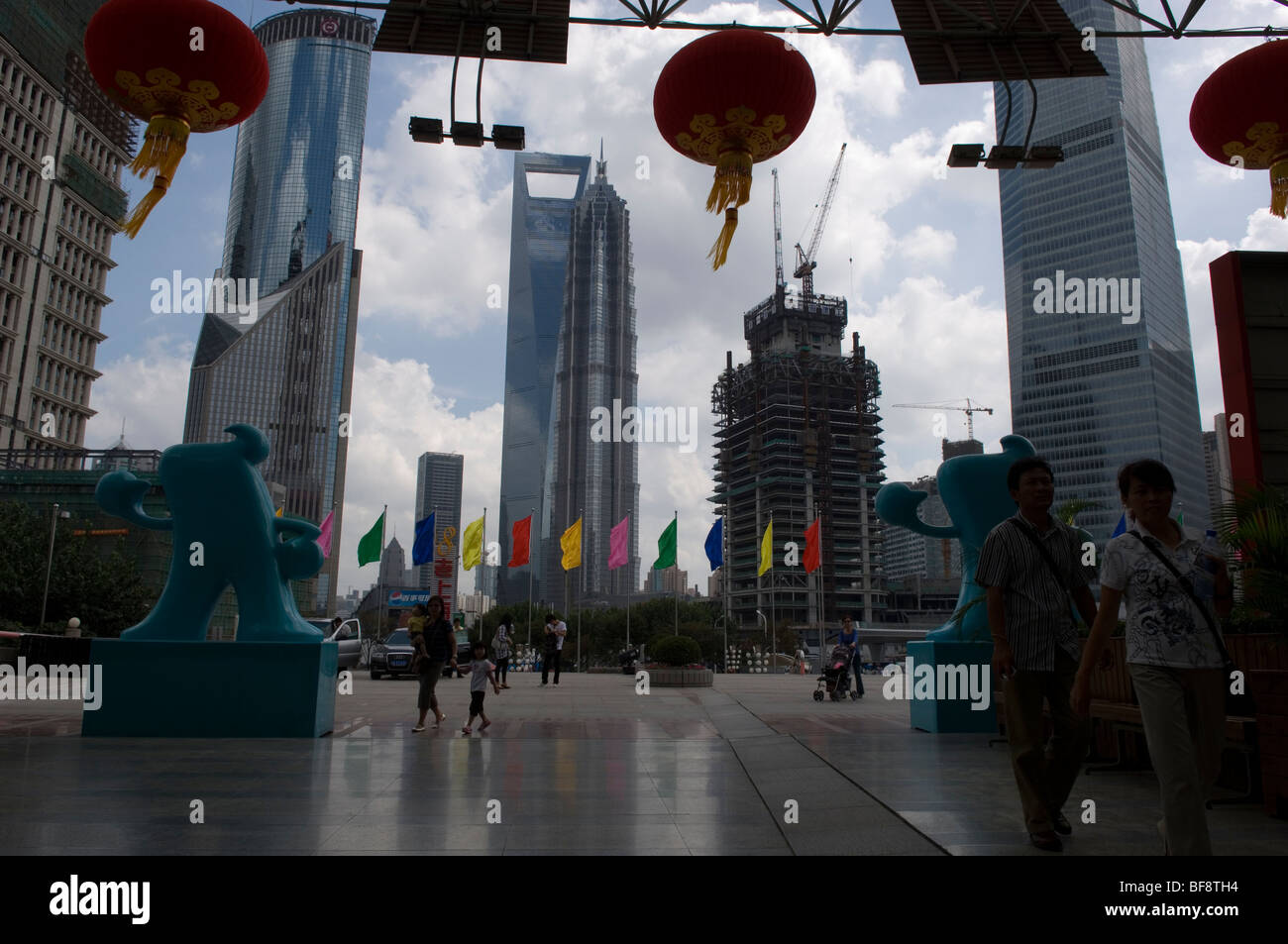 View on Pudong skyscrapers from entrance of Oriental Pearl Tower flanked by two mascots of EXPO 2010. Shanghai, China. Stock Photo