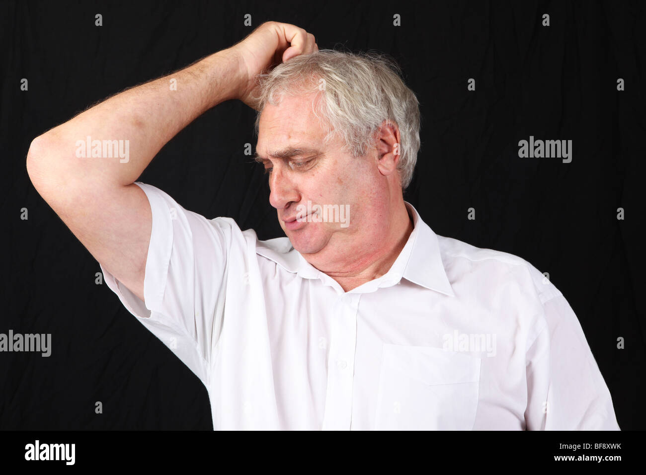 Late middle aged man sniffing smelling armpit checking for stale sweat