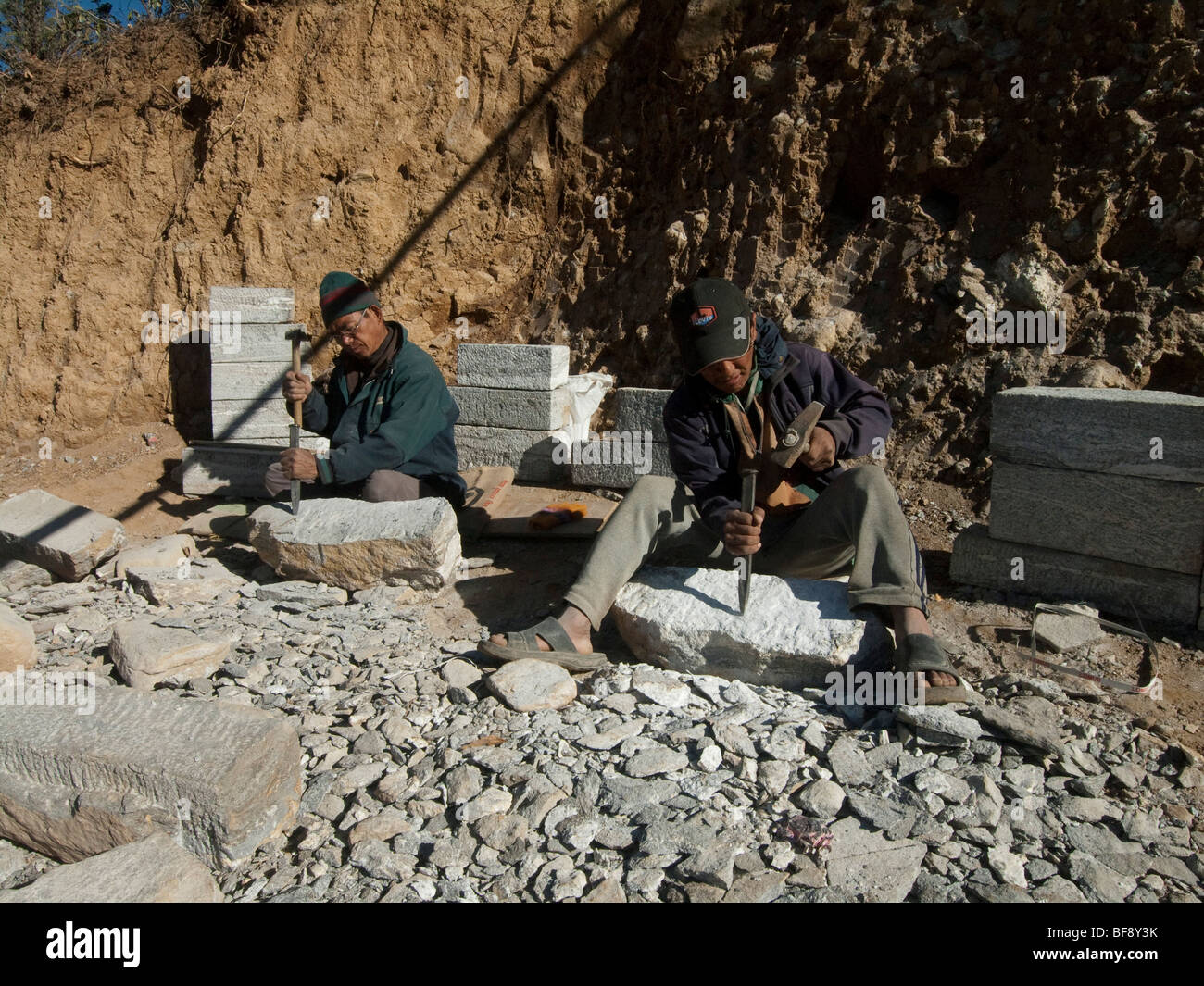 Stone masons work in quarries on the hillsides of Nepal, cutting stone blocks with hand tools