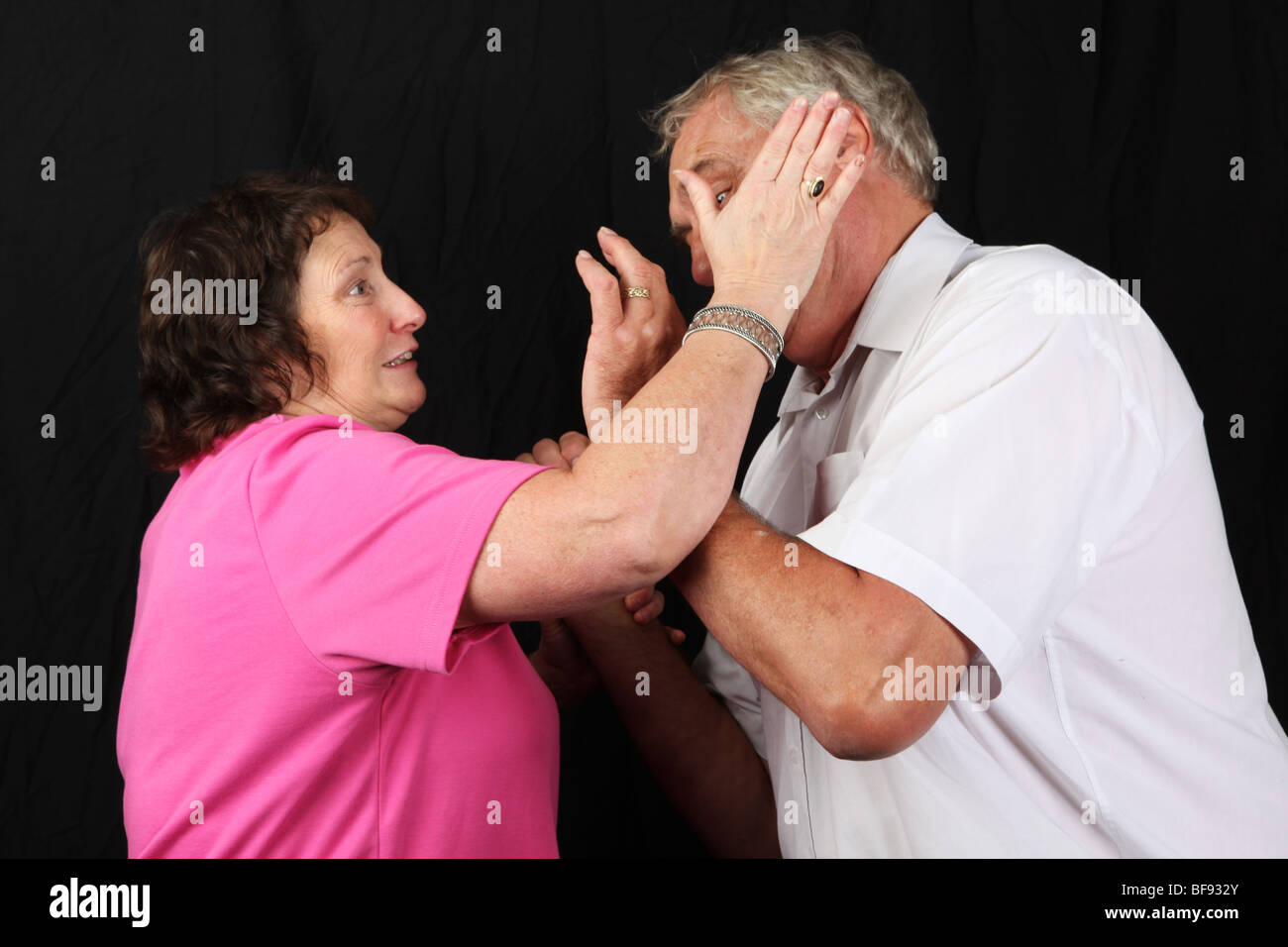 Late middle aged couple fighting wife beating husband battering punching  spousal abuse abusive relationship marriage Stock Photo
