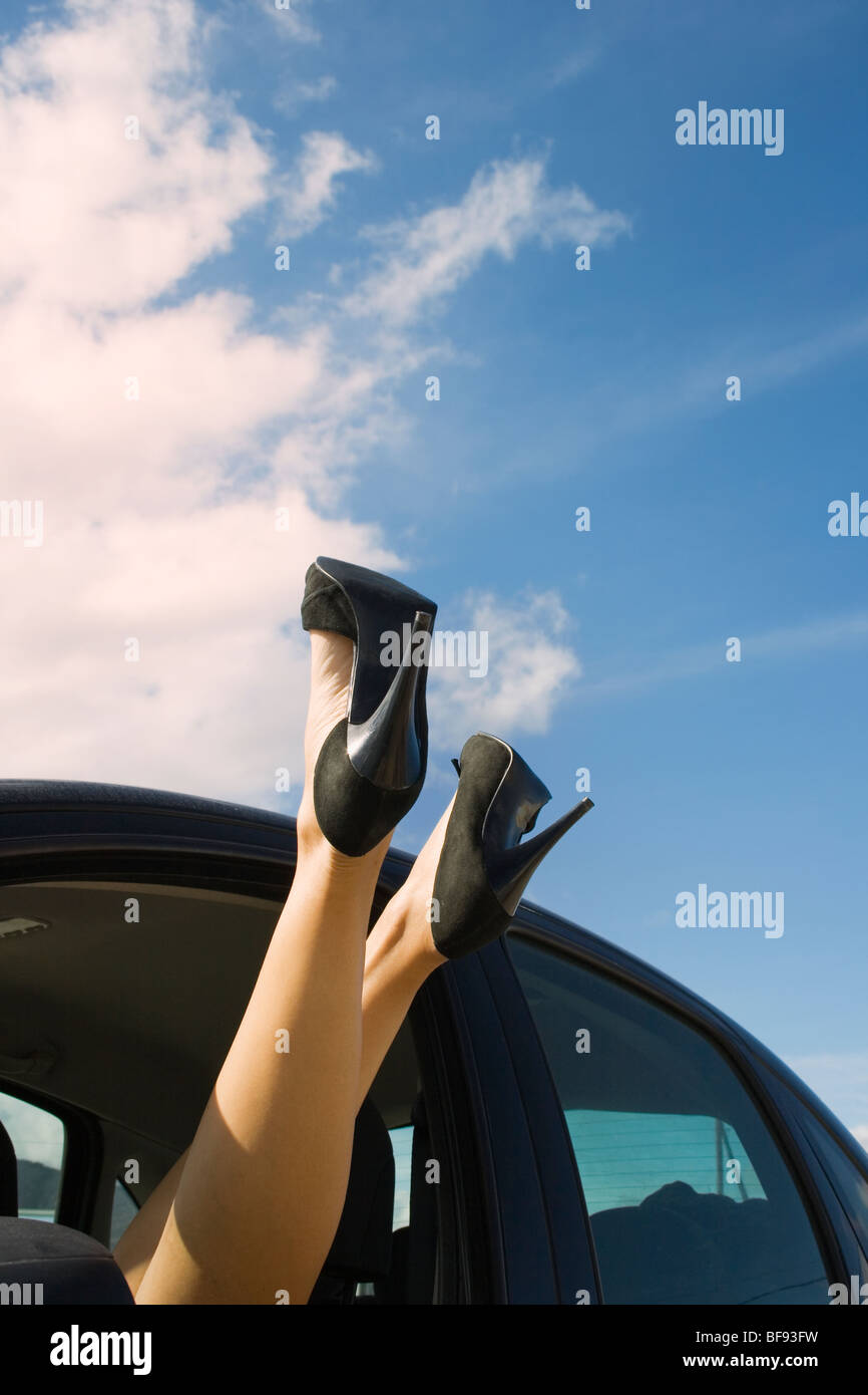 Woman's legs and feet wearing black stilletto shoes sticking out of car window Stock Photo