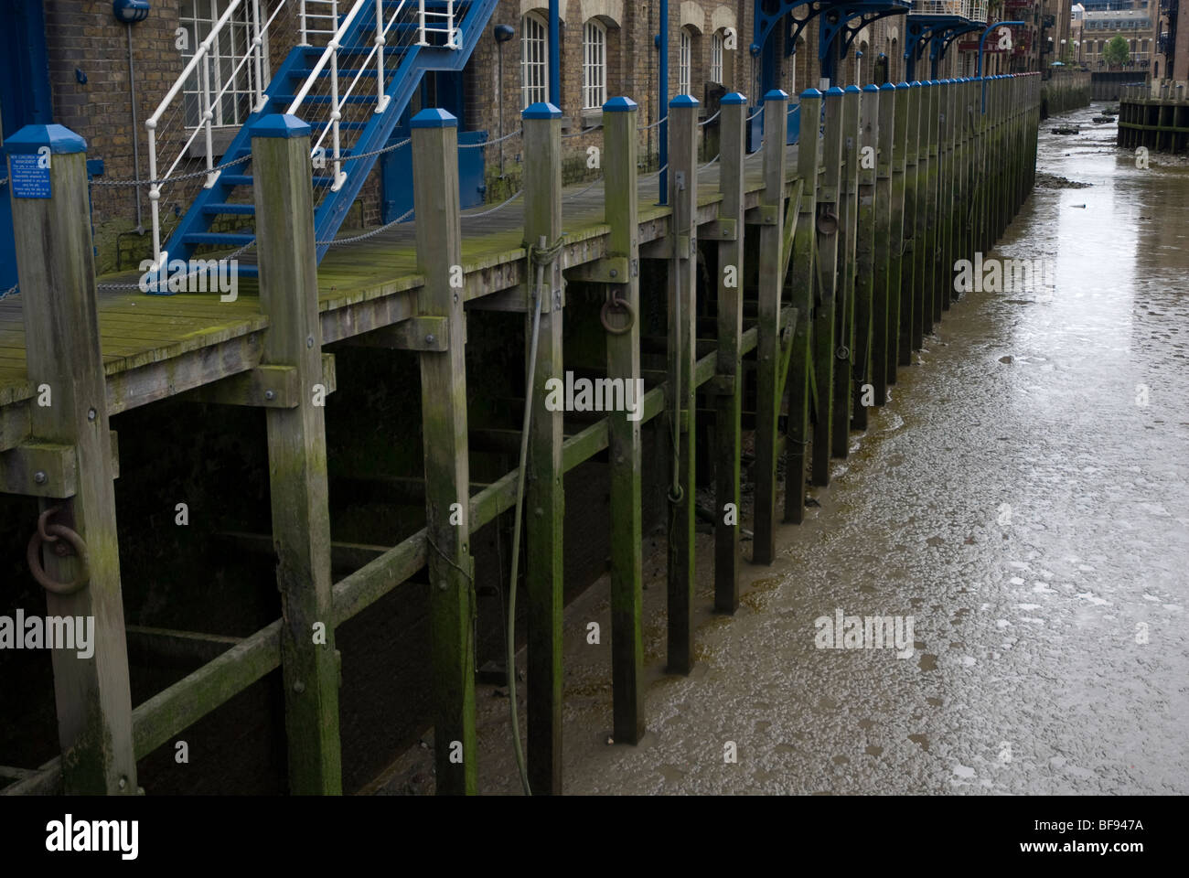 Wooden walkway on the edge of the river at low tide St Saviours Dock Docklands London SE1 Stock Photo