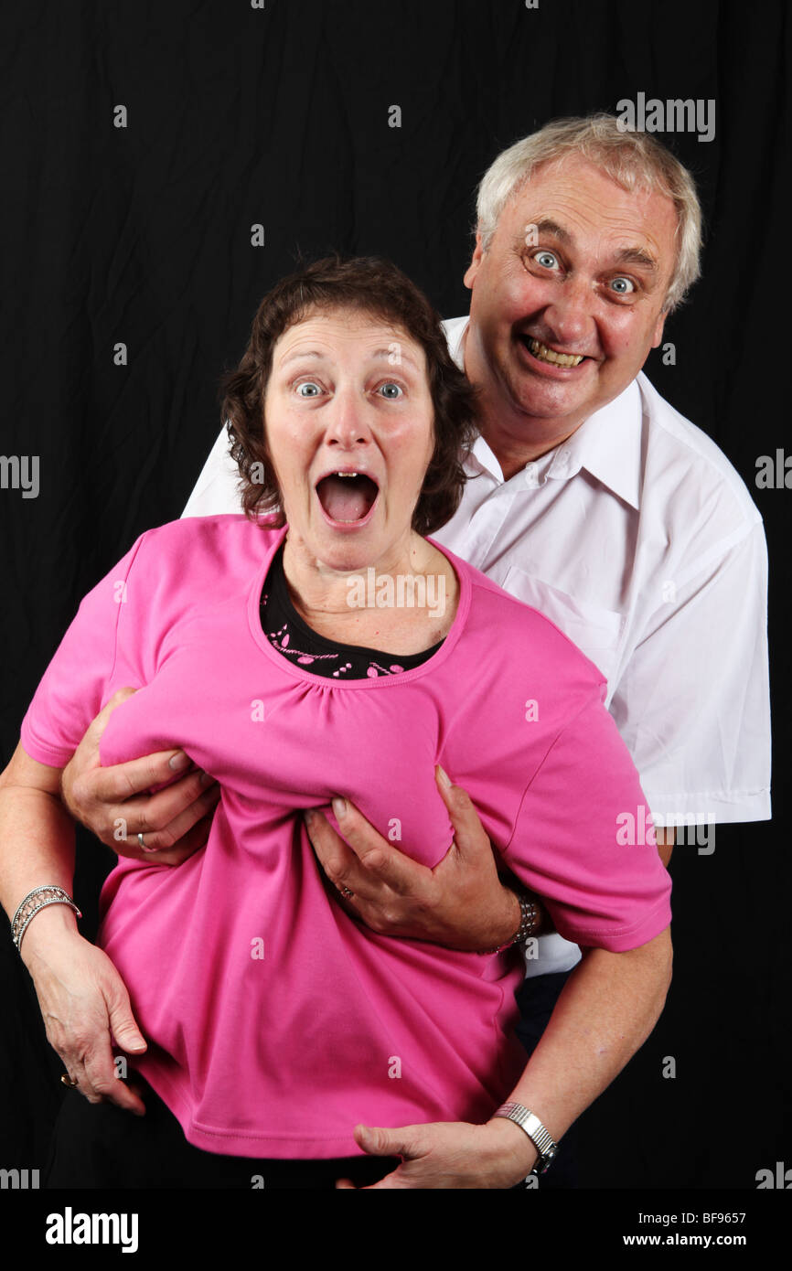 Older married couple playing laughing husband grabbing wifes boobs breasts  funny comical sexually active older grey generation Stock Photo - Alamy