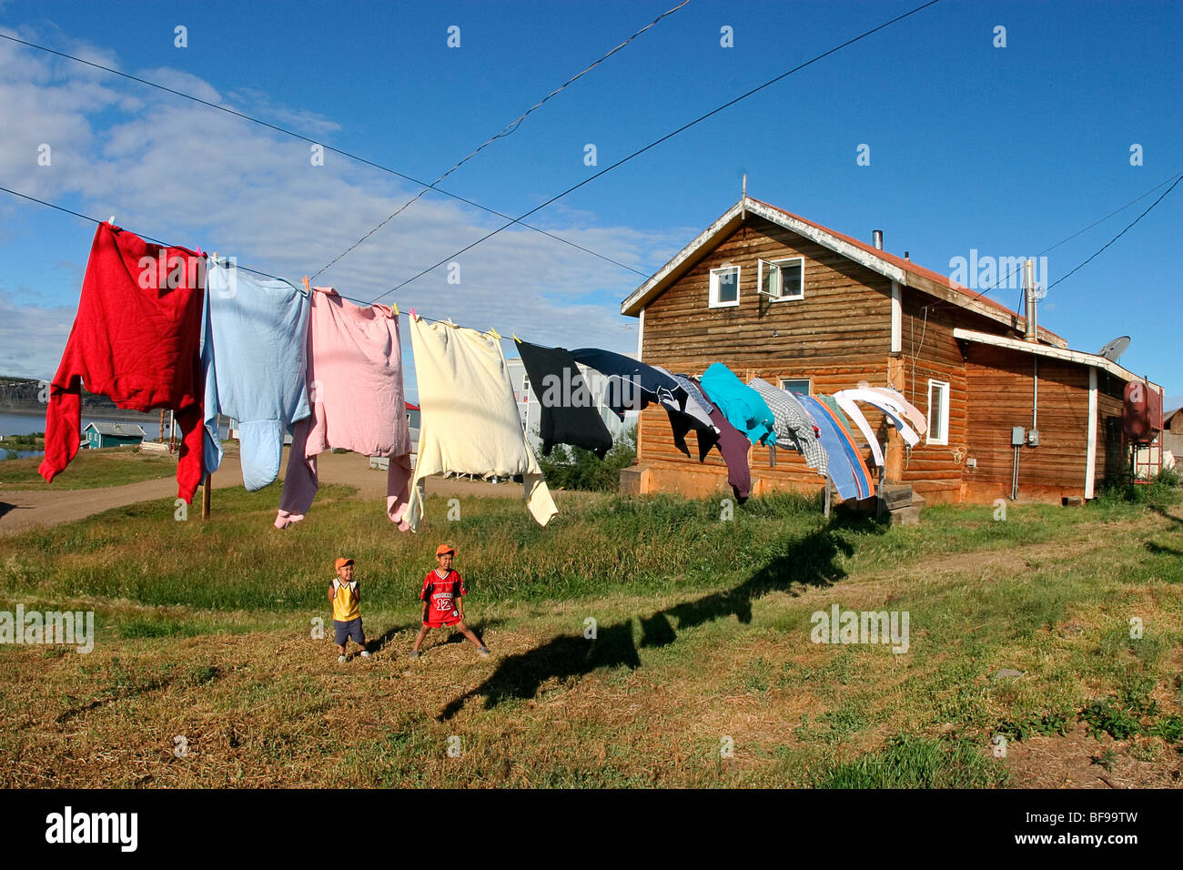 Children play in their yard while laundry dries on a line in Tsiigehtchic, village along Mackenzie River, NWT, Canada Stock Photo