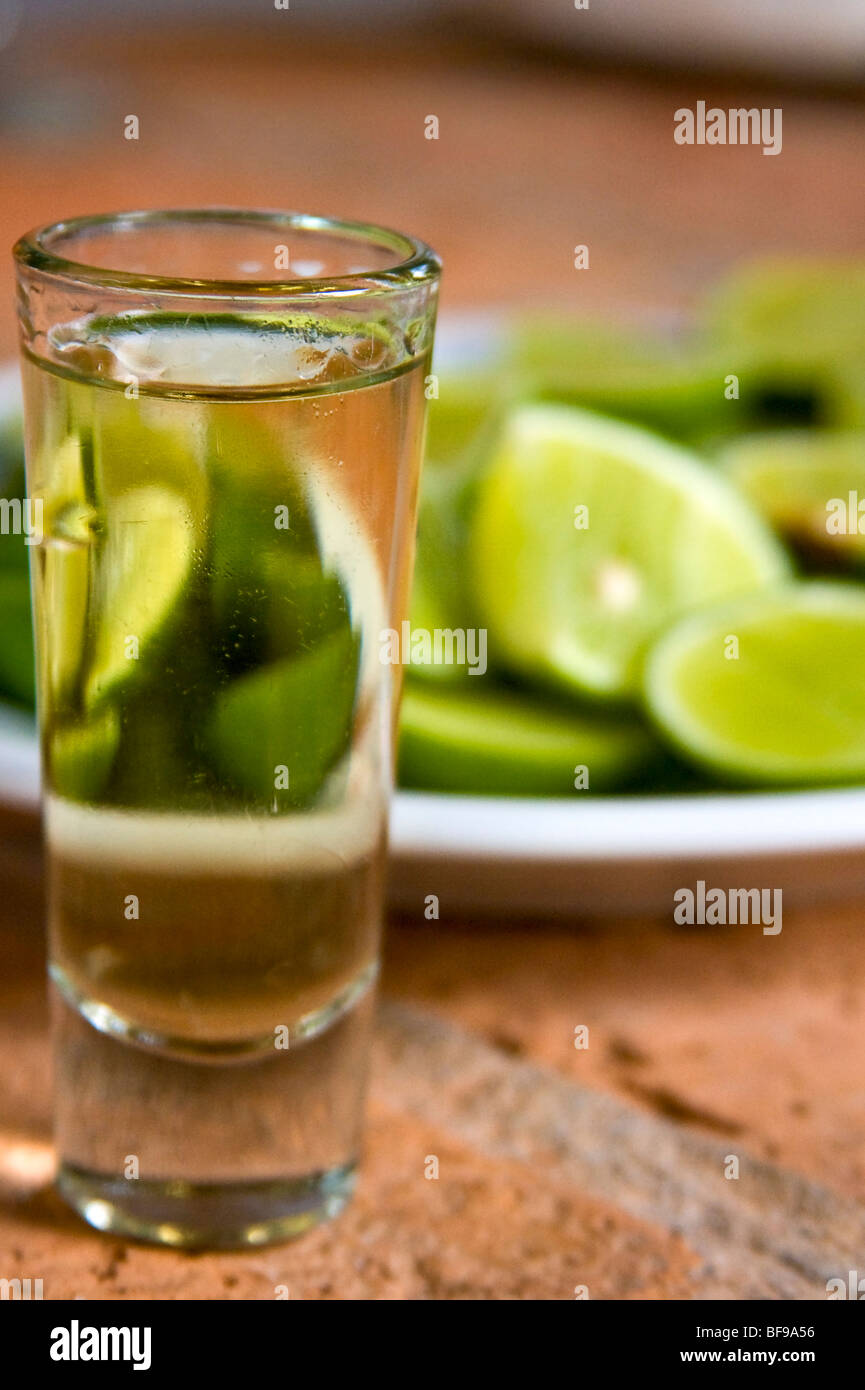 Straight shot of tequila with limes in background. Mexico Stock Photo