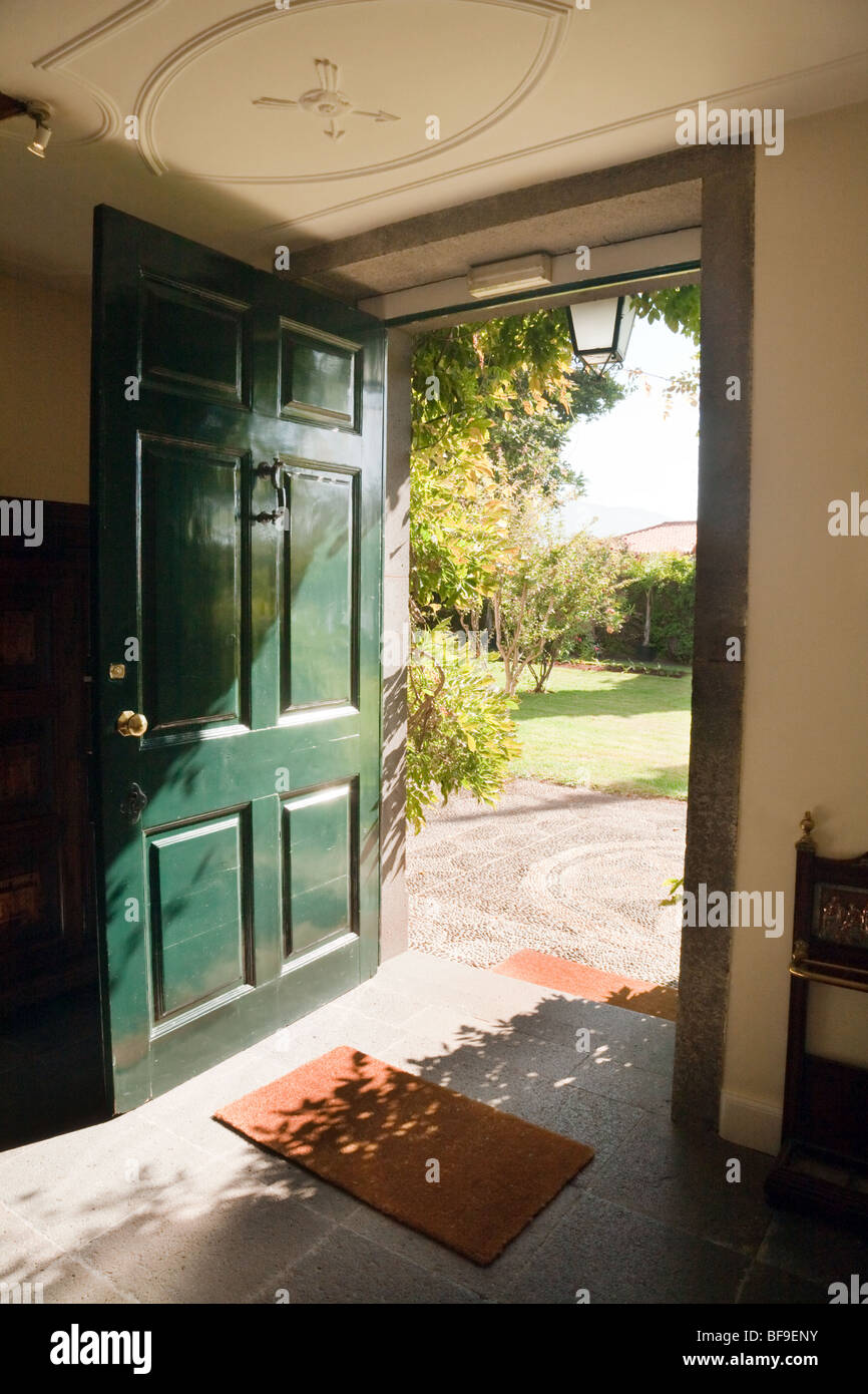 A green open door opening onto a garden on a sunny day Stock Photo