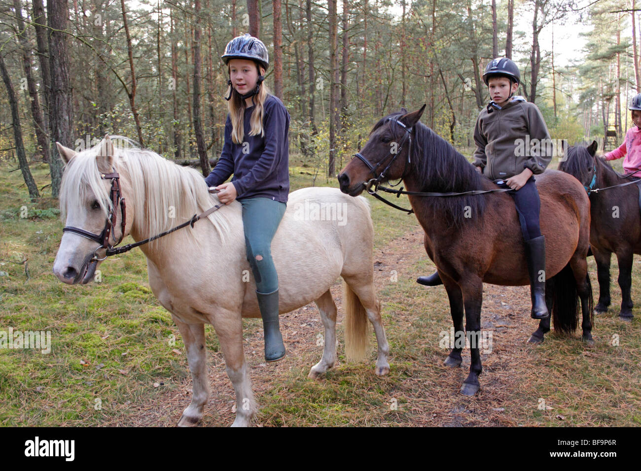 children horseback riding in a forest Stock Photo