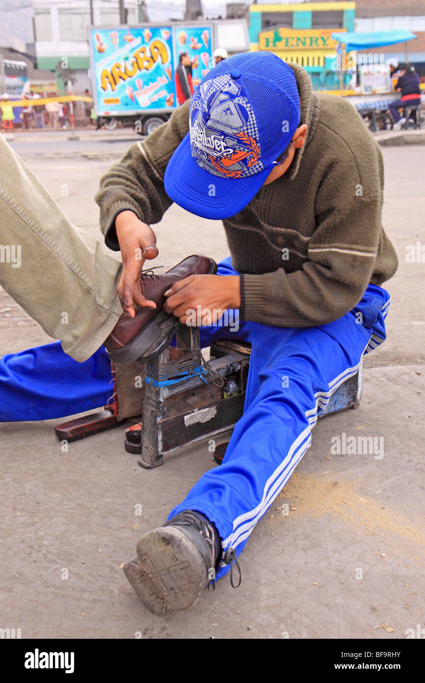 young boy shining shoes in the streets of Lima, Peru Stock Photo