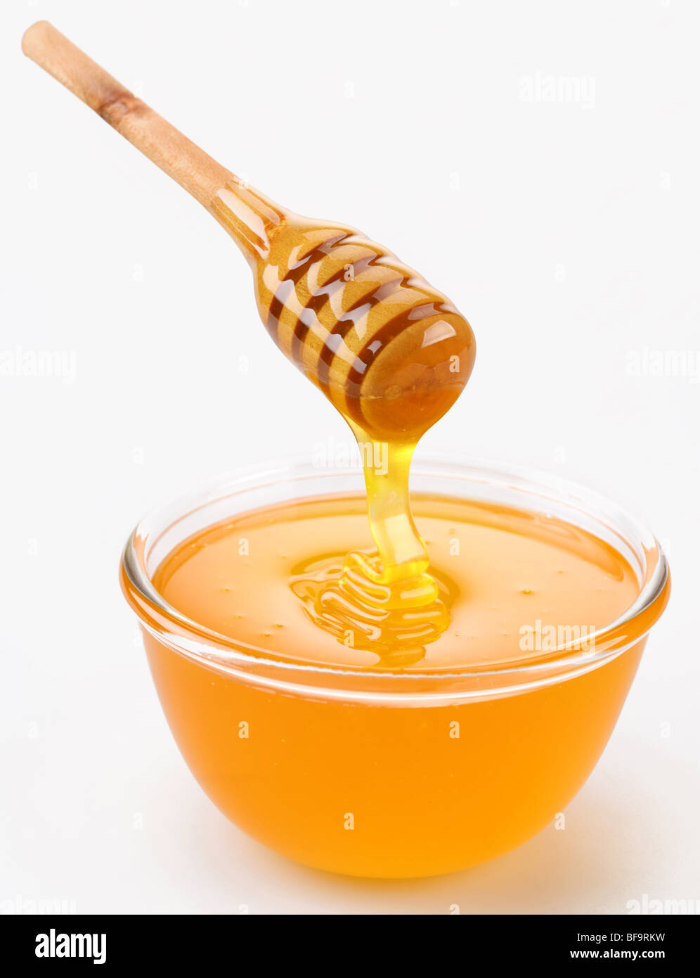 Honey pouring from stick to the bowl Stock Photo