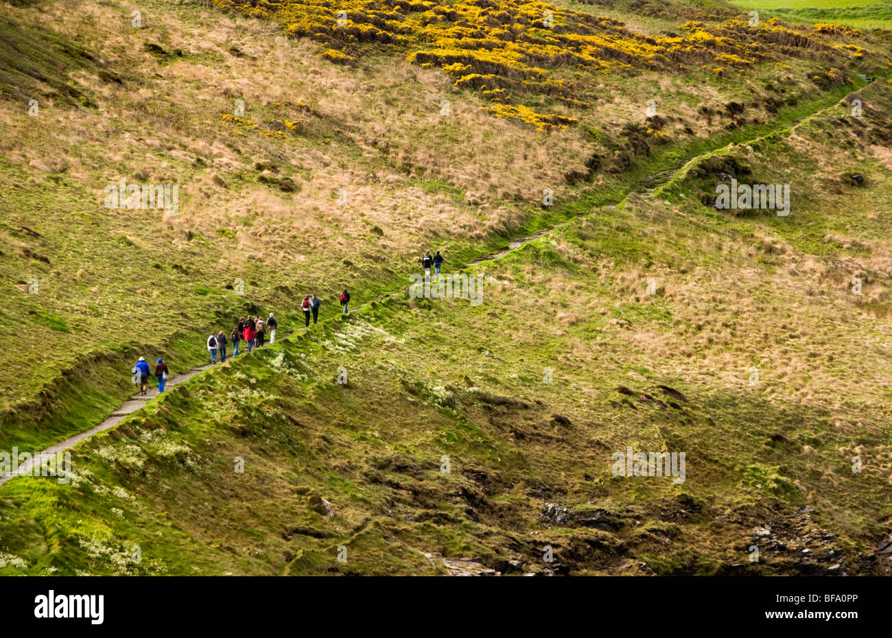 Hikers making their way up a path along the cliffs above Boscastle Harbour in Cornwall, England Stock Photo