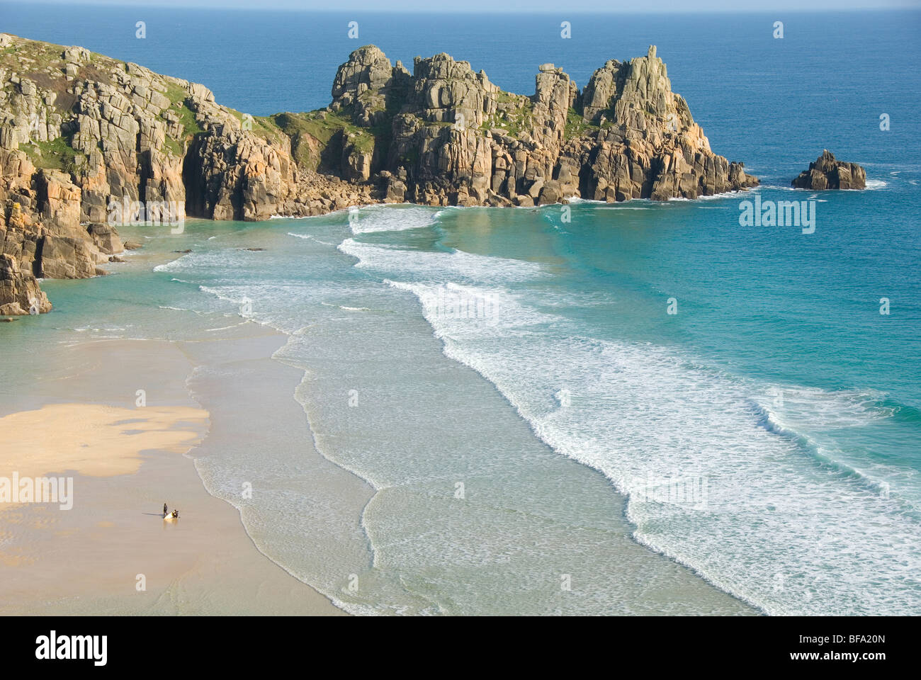 Logan Rock, two surfers coming out of water, Porthcurno Beach, Pedn Vounder Beach, South Coast, Cornwall, England, UK Stock Photo