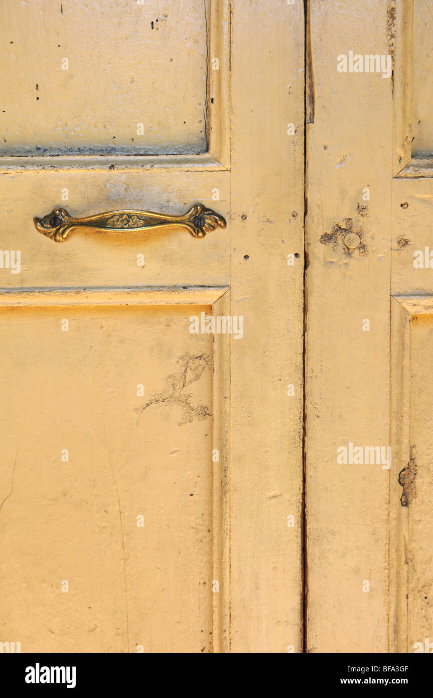 Old grunge yellow door with bronze handle Stock Photo