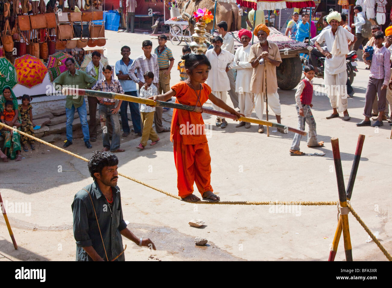 Little girl walking a tightrope at the Camel Fair in Pushkar in Rajasthan India Stock Photo