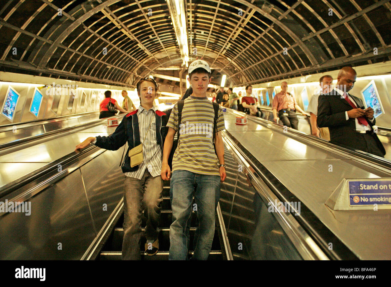 two teenage boys going down an escalator into an Underground station, London, England, Great Britain Stock Photo