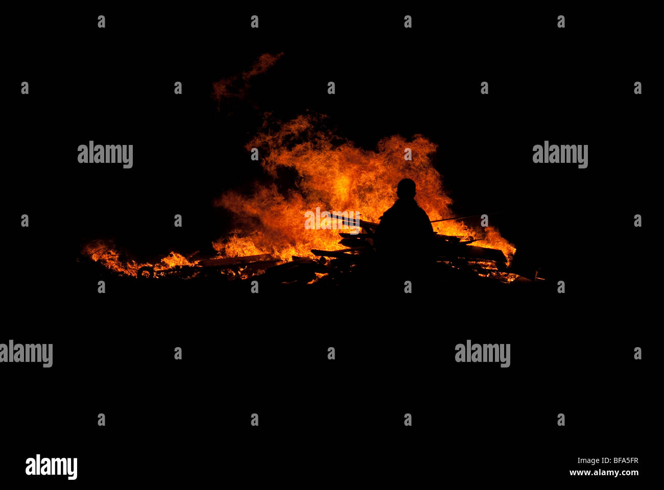 Youth silhouetted against bonfire flames at night FULLY MODEL RELEASED Stock Photo