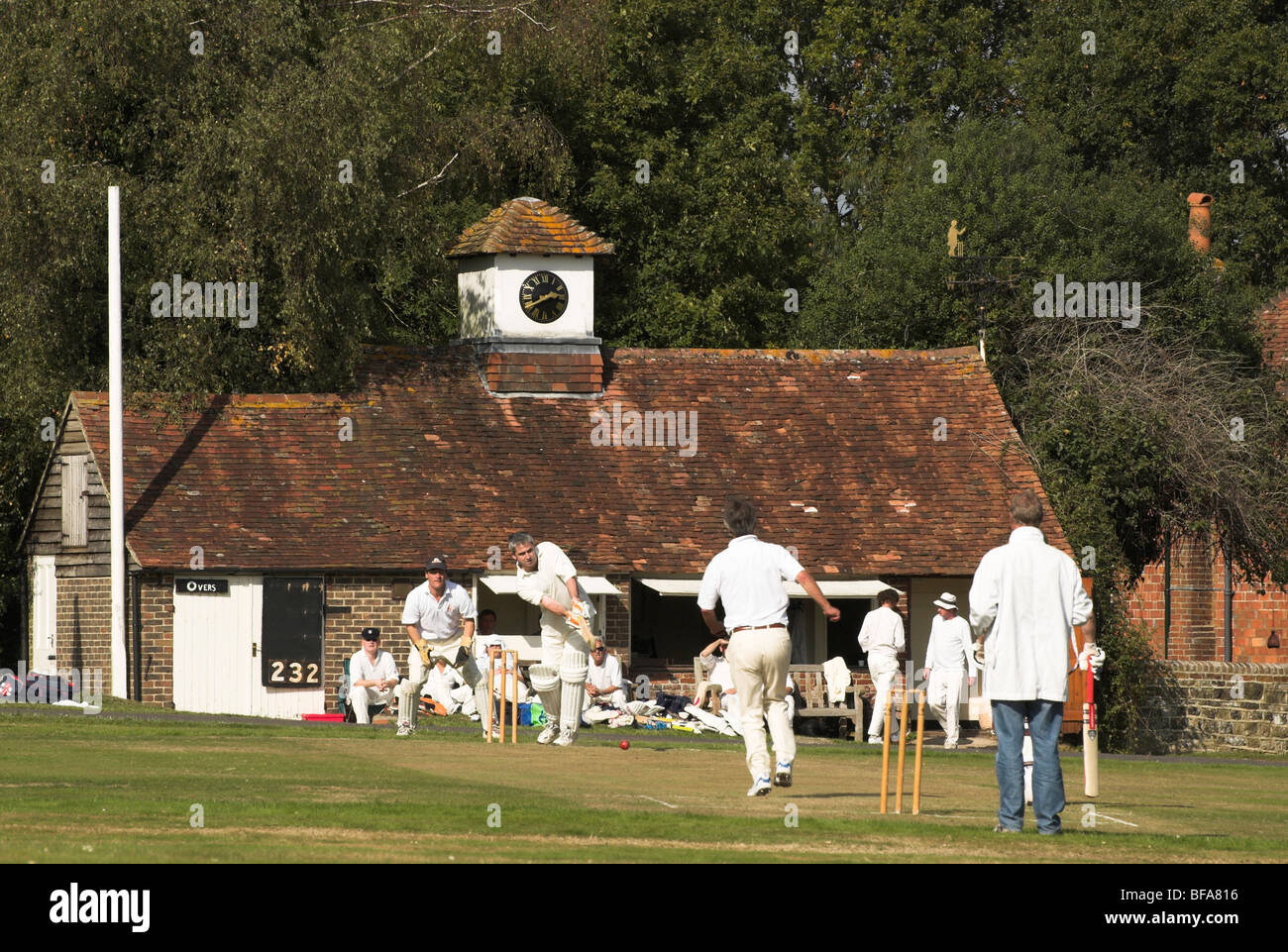 Lurgashall village green sees players participating in a game of cricket on a warm sunny autumn day. Stock Photo