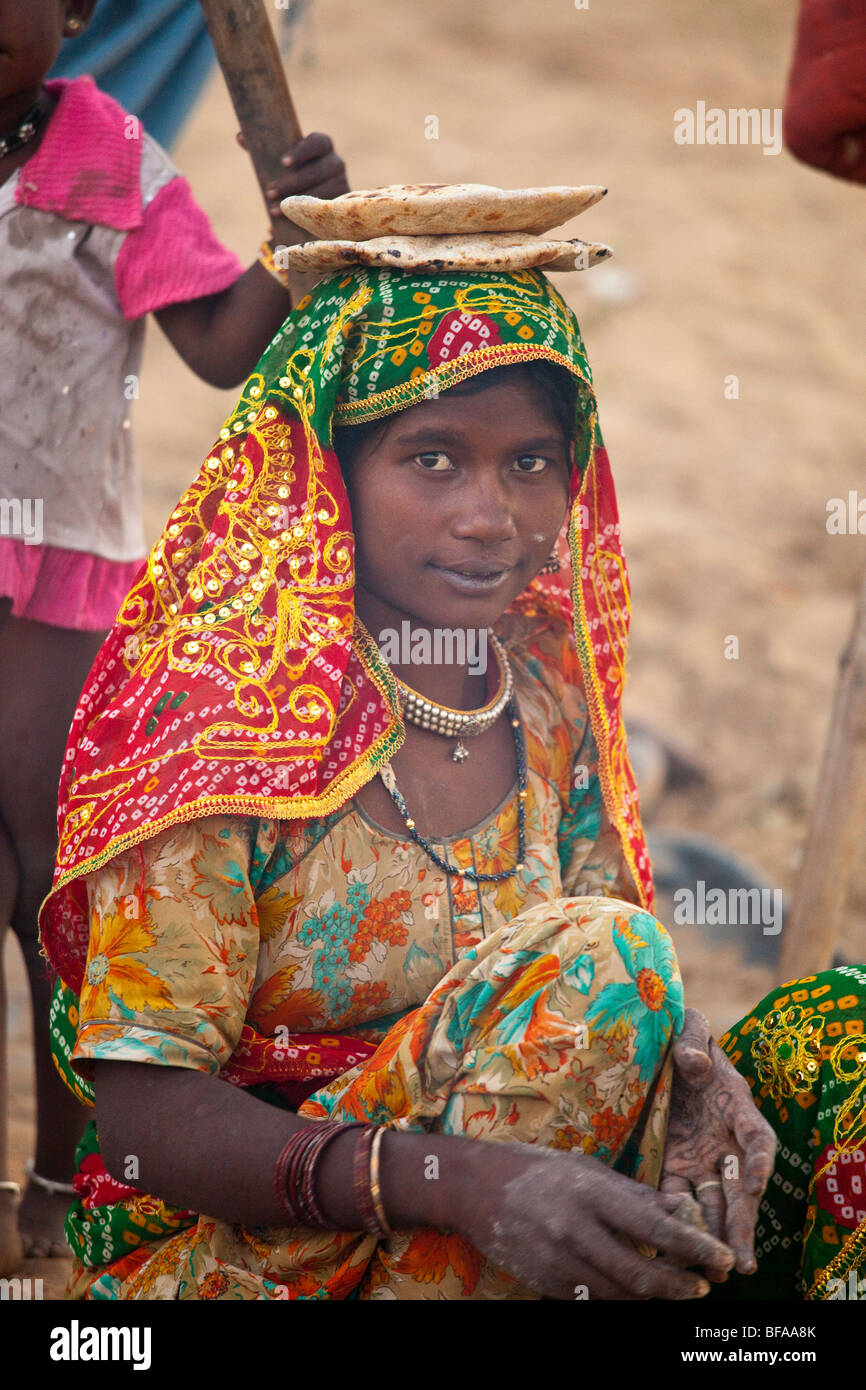 Girl making chapati and cooling them on her head at the Camel Fair in Pushkar India Stock Photo