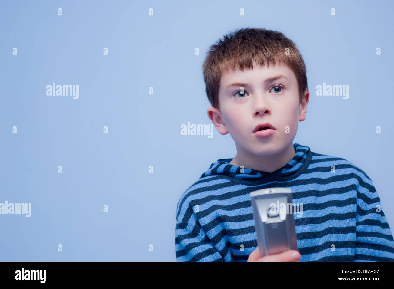 A Model Released picture of a ten year old boy with the Tv remote control indoors in the Uk Stock Photo
