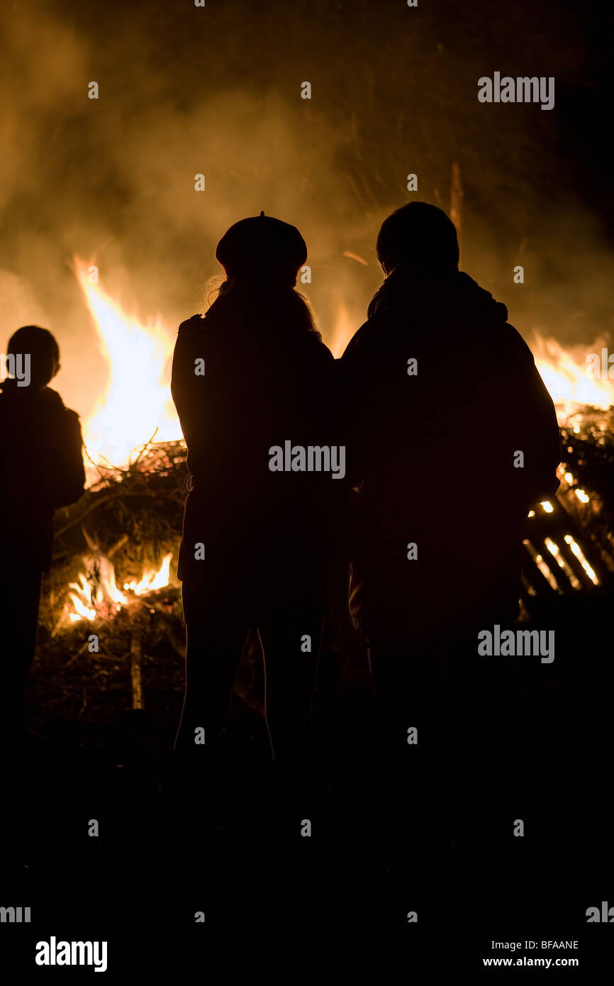 Couple and child silhouetted against a raging fire / bonfire Stock Photo