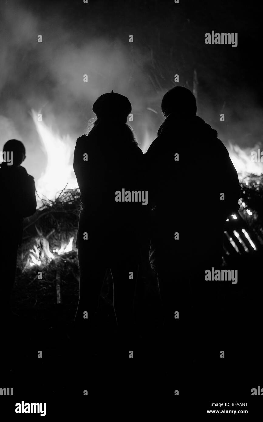 Couple and child silhouetted against a raging fire / bonfire Stock Photo